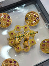 A gold-tone decorative brooch set with matching buttons, designed in a traditional ornamental style.